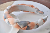 Side angle of chunky braided statement headband on white plate
