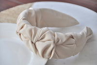 Close-up of beige ruffled headband showing gathered fabric texture and knot detail