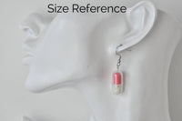 Pastel pink capsule earring shown worn on ear for size reference