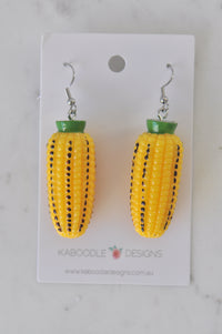 Pair of yellow resin corn cob earrings with green husk tops on Kaboodle Designs card