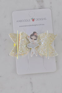 Glitter bow hair clip with resin ballerina charm on Kaboodle Designs packaging card