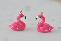 Close-up side view of two resin flamingo earrings showing curved neck and glossy finish