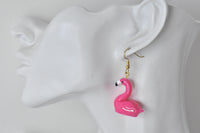 Single pink flamingo earring shown on ear for scale
