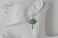 Single tree earring shown worn on ear for scale
