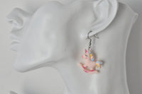 Unicorn rocking horse earring shown worn on ear for scale