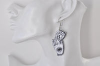 Single white Ouija hand earring with eye design worn on ear, side view