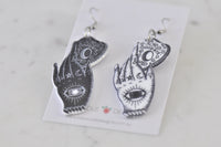 Mismatched black and white Ouija hand earrings laid flat showing full detail