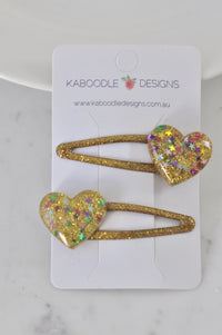 Two gold glitter heart barrette hair clips on a Kaboodle Designs branded card