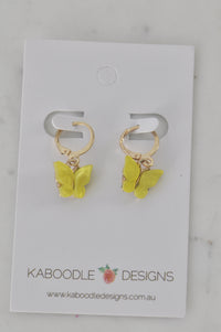 Pair of yellow acrylic butterfly earrings on gold-tone hoops, shown flat on a Kaboodle Designs card