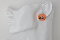 Single pumpkin face stud earring worn on ear, shown close up