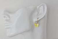Yellow butterfly hoop earring worn on an ear, shown from the side against a white background
