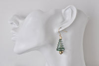 Christmas tree swirl earring shown on ear, side view against white background