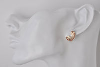 Close-up of pencil shaving stud earring worn on ear showing spiral shape and scale
