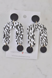 Pair of black and white speckled acrylic horseshoe-arch earrings on Kaboodle Designs card