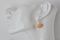 Single mandarin earring shown dangling from an ear for scale