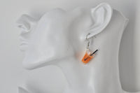 Close-up of orange juice earring worn on ear showing straw and citrus slice detail