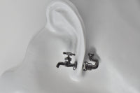 Close-up of gold tap and pipe stud earrings worn on ear