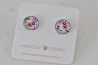 Round stud earrings with pink, orange and navy floral artwork under glossy dome, on Kaboodle card