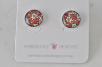 Round stud earrings with rust red, sage and aqua floral artwork under glossy resin