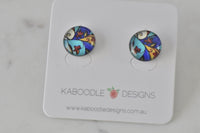 Round stud earrings with blue, turquoise and yellow stained-glass style artwork and red flower detail