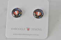 Round folk-art flower stud earrings on card, showing red tulip design on black background
