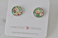 Round stud earrings with vintage rose print in red, cream and green under glossy dome, on Kaboodle card