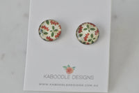 Round stud earrings with rust red and green floral pattern on cream, glossy finish, shown on Kaboodle card