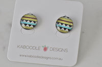 Round stud earrings with Aztec zigzag pattern in mustard, teal and black on Kaboodle card