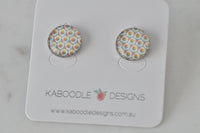 Round stud earrings with colourful honeycomb pattern artwork under glossy clear cover, pair shown on Kaboodle card