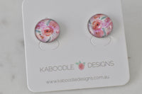 Round floral artwork stud earrings in pink and coral tones on Kaboodle Designs card