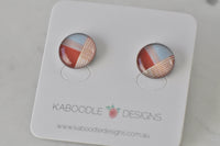 Round stud earrings with geometric rust, blue and striped pattern on Kaboodle card