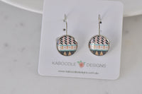 Round leverback earrings on Kaboodle Designs card, showing Aztec chevron and triangle pattern in black, pink, teal and gold