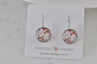 Round leverback earrings with white floral print on red background, shown on Kaboodle Designs card