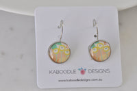 Round leverback earrings on card with yellow floral pattern under glossy resin