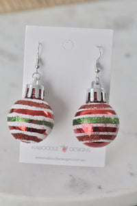 Pair of red bauble drop earrings with glitter stripes on white card backing