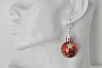 Close-up of red glitter-star bauble earring worn on ear, side view