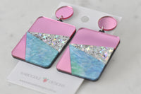 Pair of colour-block acrylic earrings angled to show glitter and marble detail