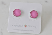Round pink stud earrings with glossy domed finish on Kaboodle Designs card