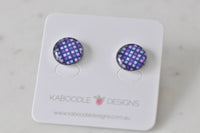 Round stud earrings with purple, pink and mint checkerboard pattern under glossy resin, shown on card