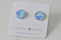 Round stud earrings with blue, white and yellow watercolour-style artwork on card