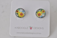 Round sunflower artwork stud earrings with yellow petals and green foliage on Kaboodle card