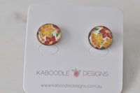 Round stud earrings with red, orange and yellow floral artwork on white background