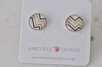 Round stud earrings on card with colourful zigzag chevron pattern in black, yellow, coral and mint