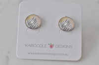 Round stud earrings with cream, blush and black striped artwork design on a Kaboodle Designs card