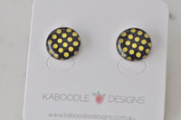 Round stud earrings with gold polka dot pattern on black, glossy domed finish, front view
