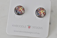 Round stud earrings with multicoloured floral artwork under glossy resin dome, shown on card