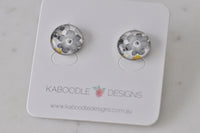 Pair of round grey and white floral stud earrings with mustard yellow accent, on Kaboodle Designs card