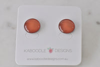 Round terracotta-orange artwork stud earrings on a Kaboodle Designs card, glossy domed finish
