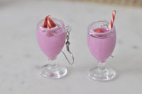 Front view of milkshake dangle earrings showing glass stem, pink shake and watermelon garnish