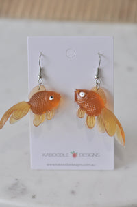 Pair of orange rubber goldfish dangle earrings on Kaboodle Designs card, facing each other
